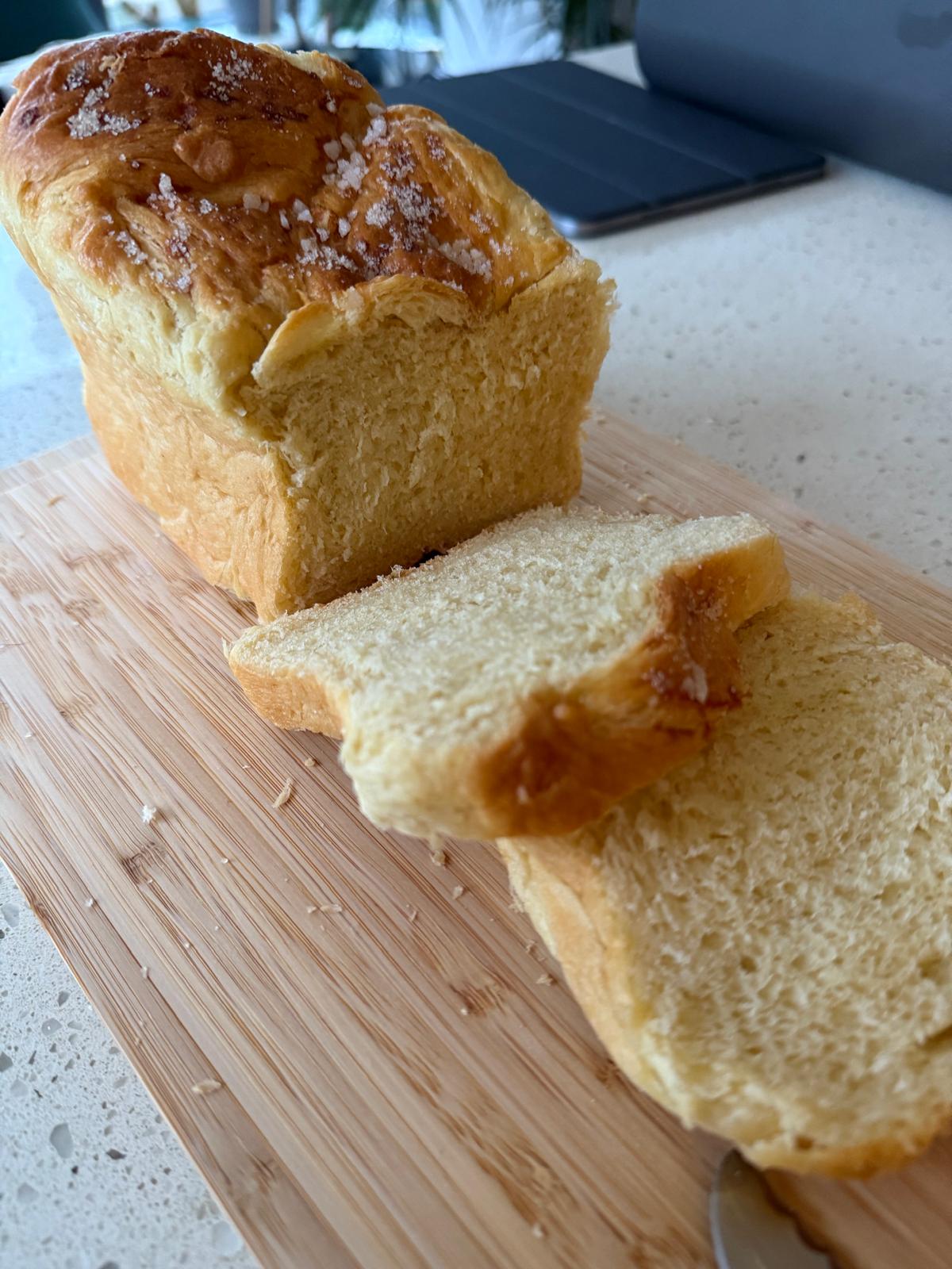 Milk bread loaf and slices on a wooden board